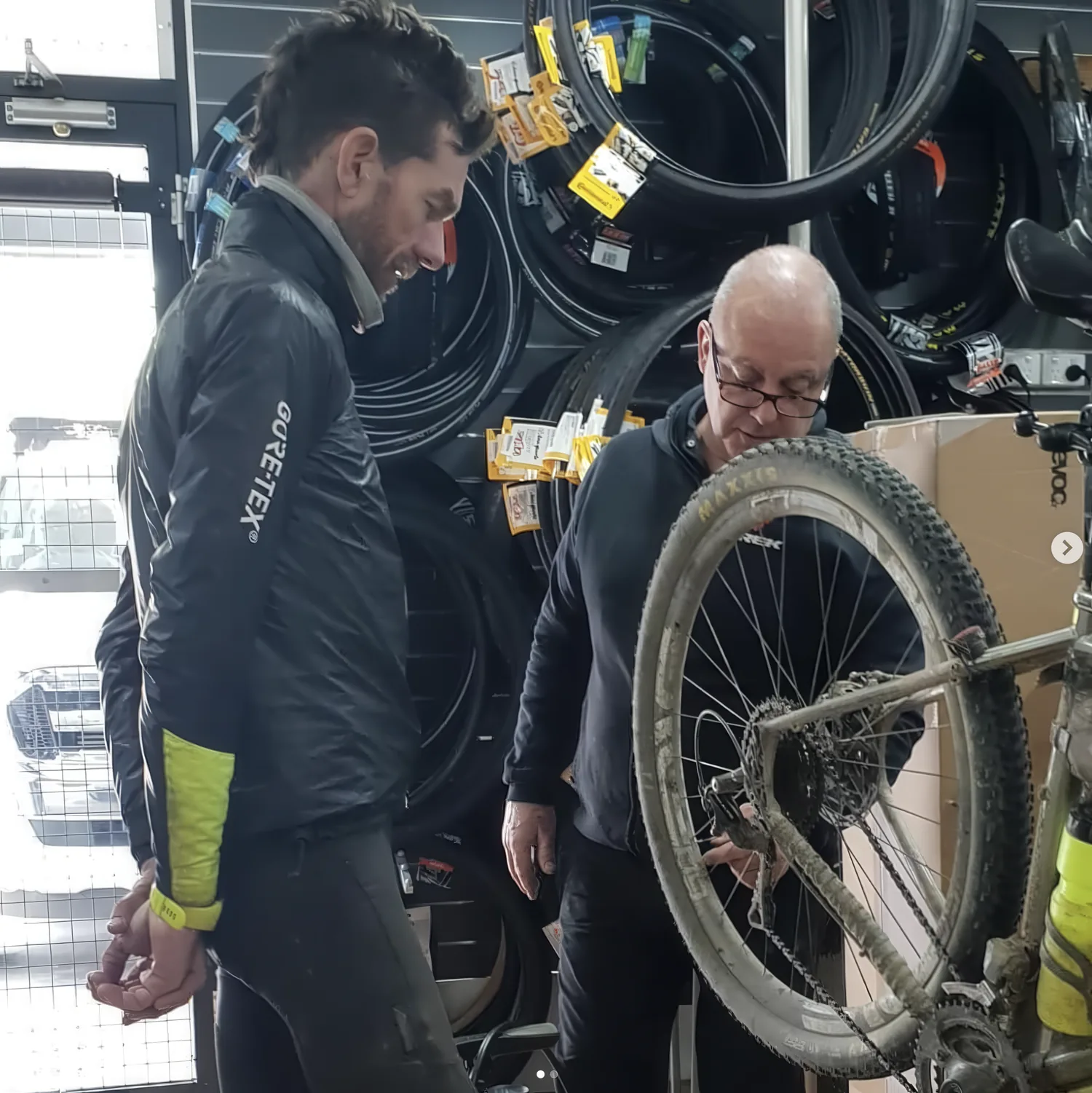 A customer and staff member looking over a muddy mountain bike wheel at the counter